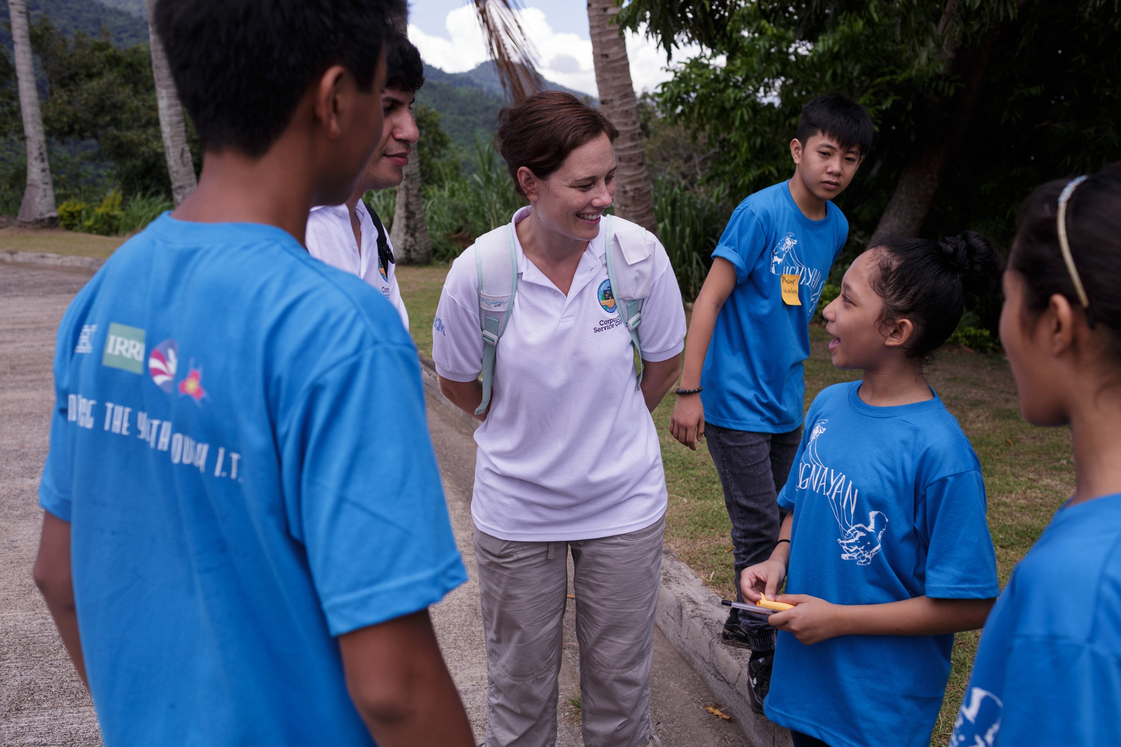 A female IBMer talks to four children in a tropical environment