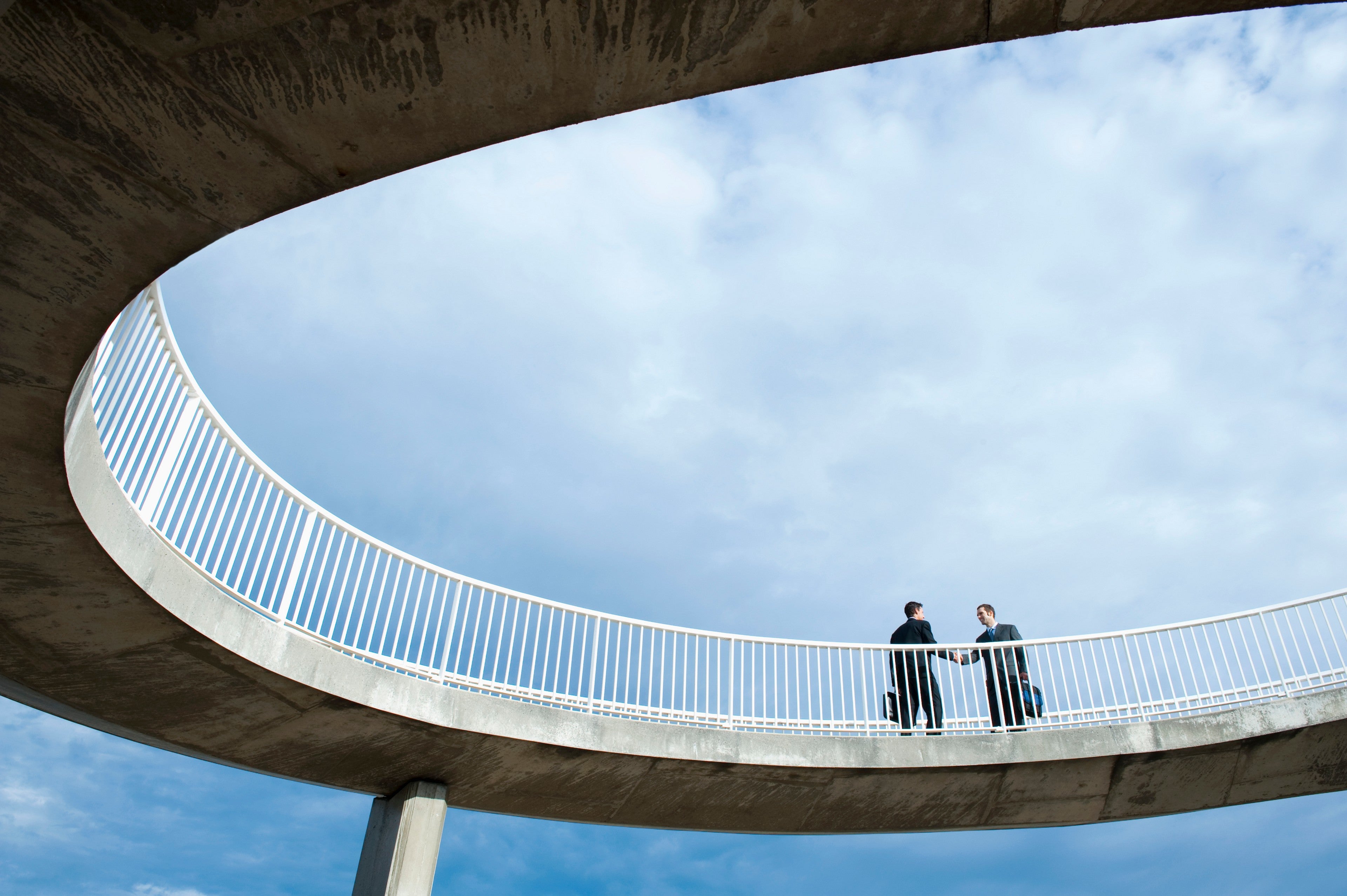 Caucasian businessmen shaking hands on elevated walkway