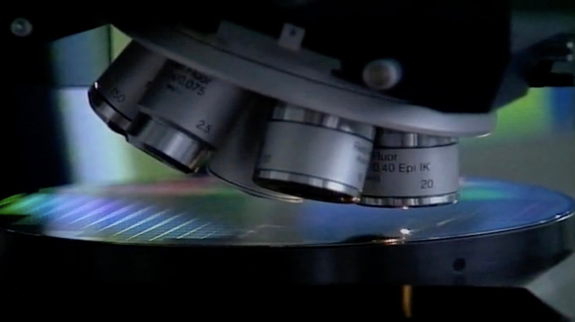 Close-up view of a microscope with several lenses focused on a silicon germanium chip