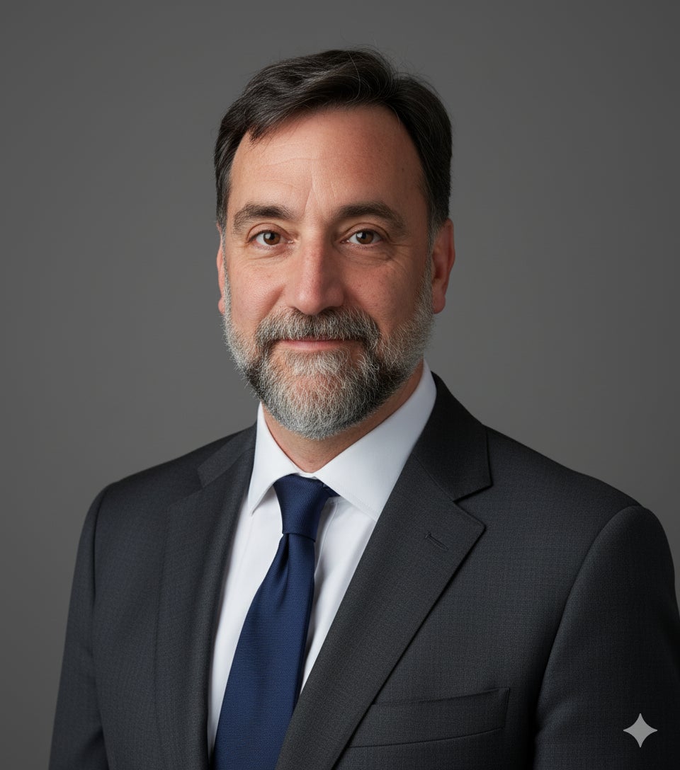 headshot of John Velisaris wearing a dark suit 