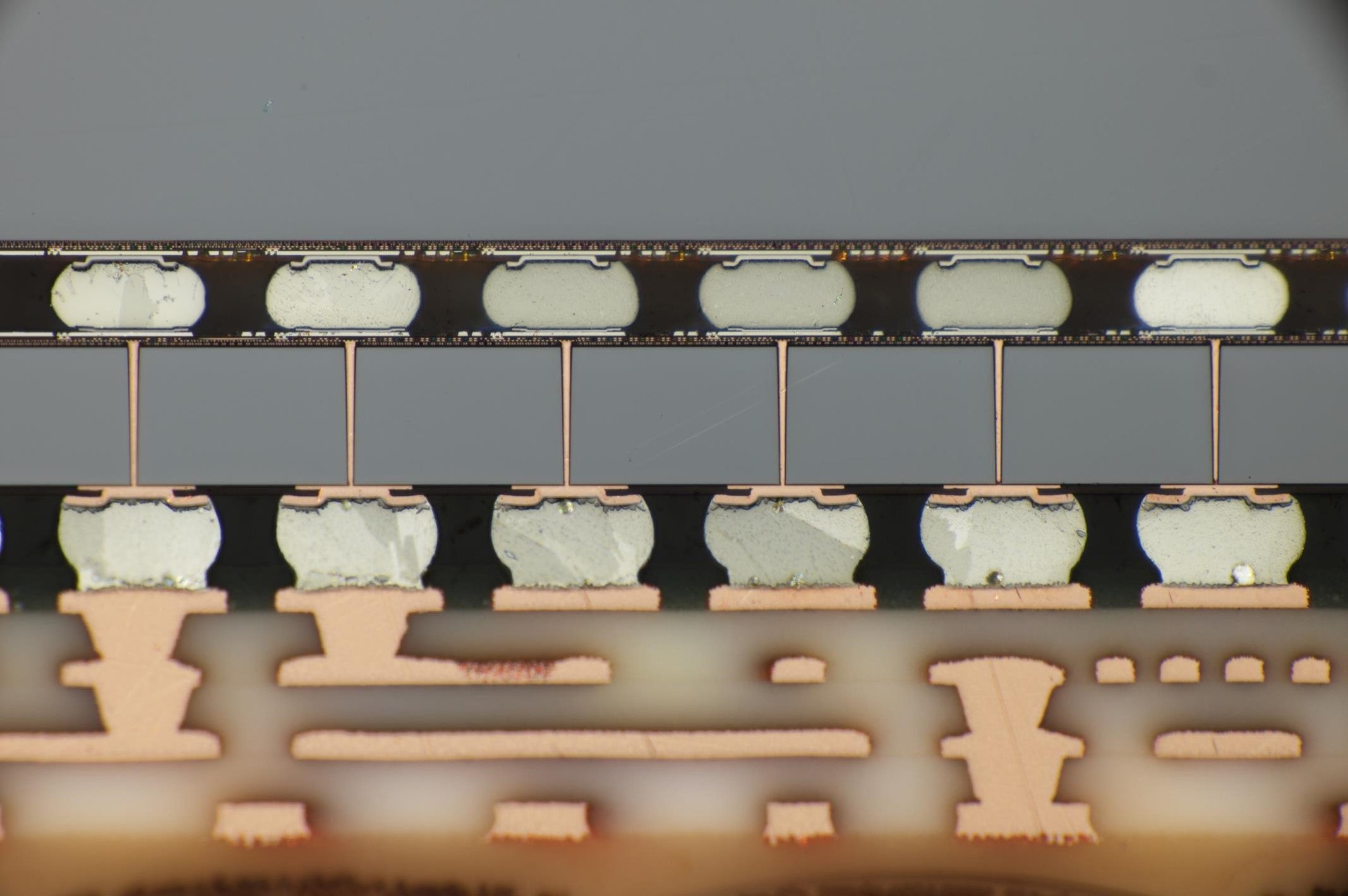 Close-up cross-sectional view of layered electronic components with solder joints and metallic interconnects